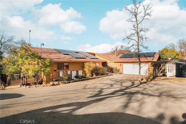 view of front facade with a carport, a garage, and solar panels