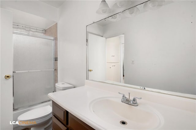 full bathroom featuring vanity, enclosed tub / shower combo, and toilet