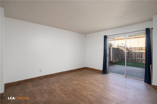 empty room with hardwood / wood-style flooring and a textured ceiling