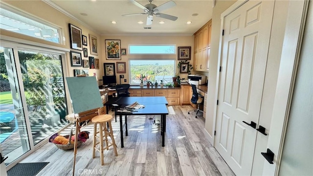 home office with crown molding, ceiling fan, built in desk, and light hardwood / wood-style flooring