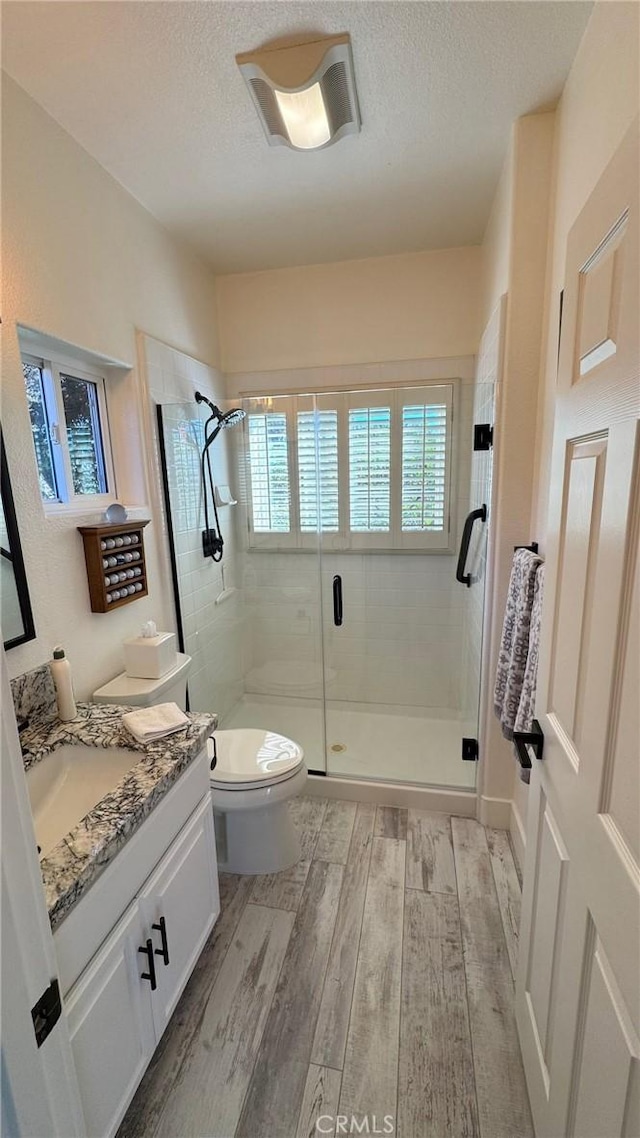 bathroom featuring toilet, an enclosed shower, wood-type flooring, a textured ceiling, and vanity