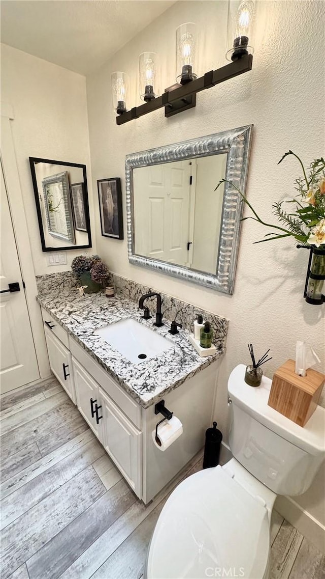 bathroom with vanity, toilet, and hardwood / wood-style floors