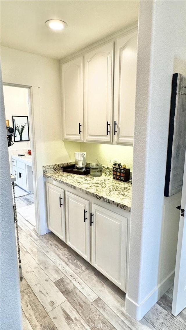 bar with light stone countertops and white cabinets