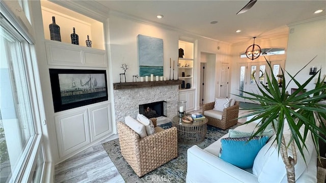 living room featuring crown molding, a stone fireplace, light hardwood / wood-style floors, and built in features