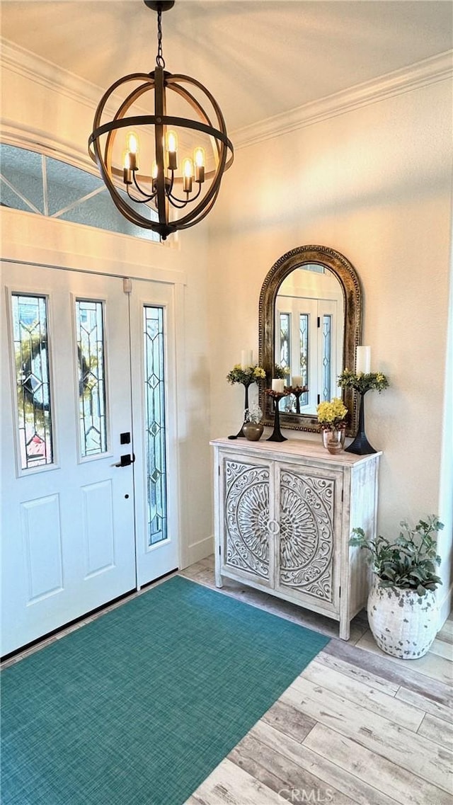 entryway featuring ornamental molding, a wealth of natural light, hardwood / wood-style floors, and a chandelier