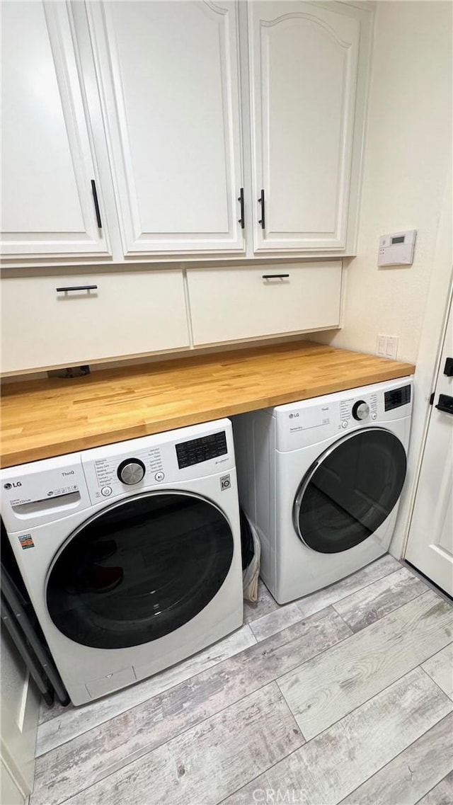 washroom featuring light hardwood / wood-style flooring, washer and clothes dryer, and cabinets