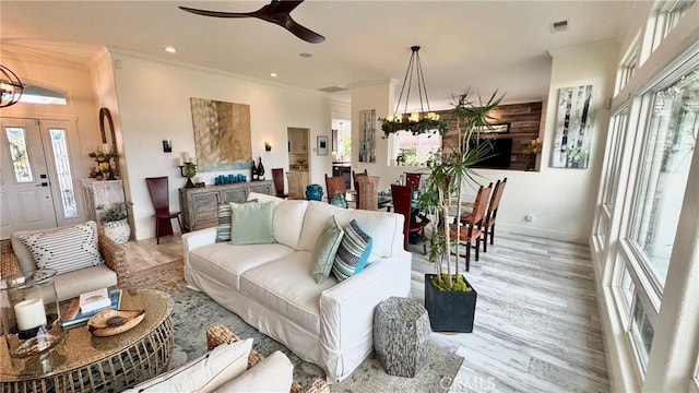 living room with crown molding, ceiling fan with notable chandelier, and light hardwood / wood-style floors