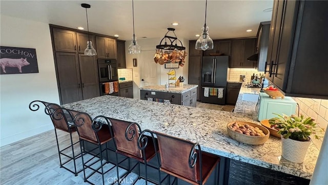 kitchen featuring decorative light fixtures, a kitchen island, light stone countertops, and black fridge