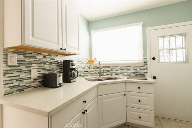 kitchen with tasteful backsplash, light tile patterned flooring, sink, and white cabinets