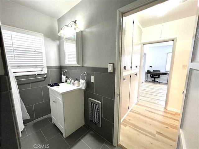 bathroom featuring vanity, wood-type flooring, and tile walls