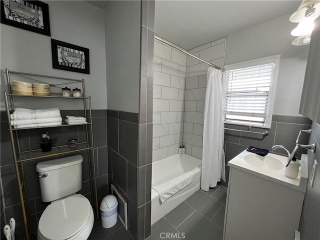 full bathroom with tile patterned floors, toilet, tile walls, vanity, and shower / bath combo with shower curtain