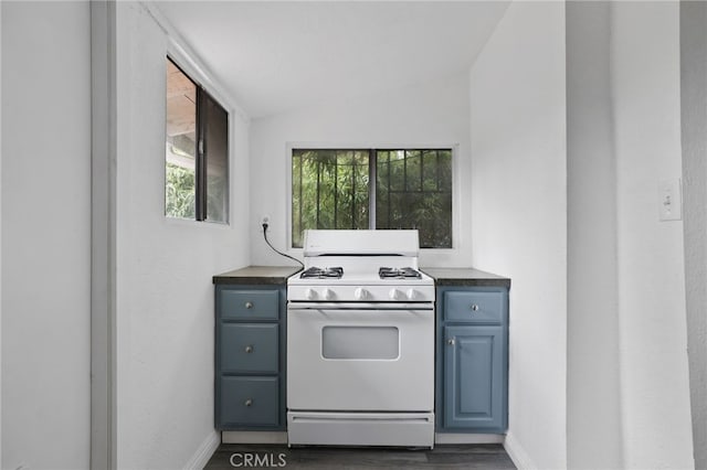 kitchen featuring dark wood-type flooring, vaulted ceiling, and gas range gas stove