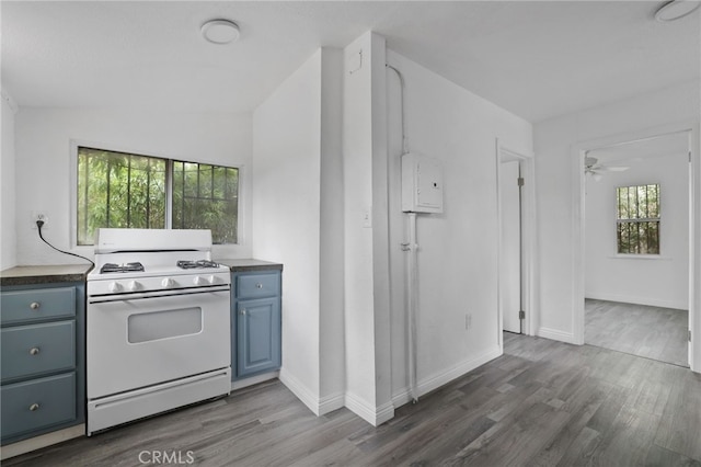 kitchen featuring ceiling fan, dark wood-type flooring, blue cabinetry, and gas range gas stove