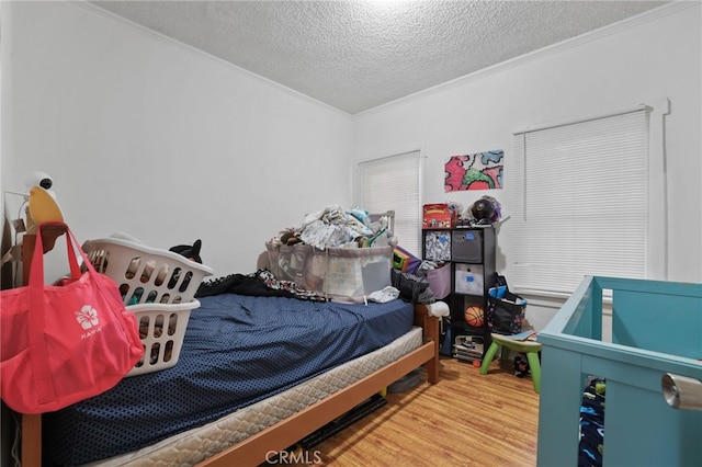 bedroom with wood-type flooring, crown molding, and a textured ceiling