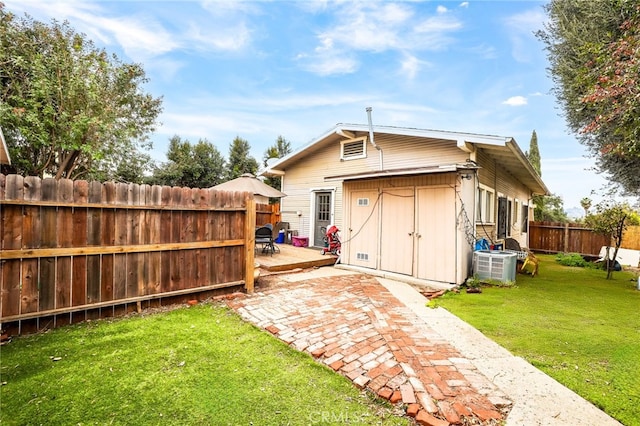 rear view of house featuring a storage shed, a yard, central AC unit, and a deck