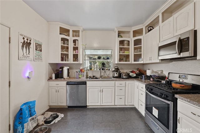 kitchen featuring sink, white cabinetry, stainless steel appliances, dark tile patterned flooring, and decorative backsplash