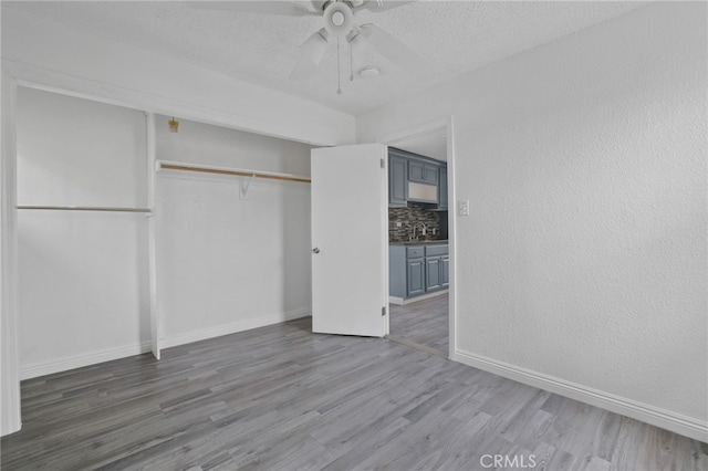 unfurnished bedroom featuring hardwood / wood-style floors, sink, ceiling fan, a textured ceiling, and a closet