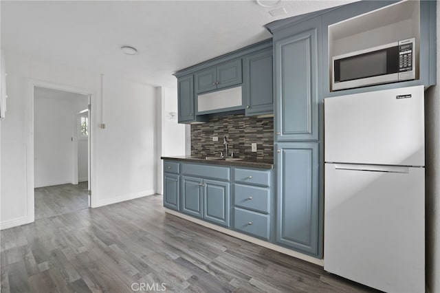 kitchen featuring blue cabinets, white fridge, sink, and decorative backsplash