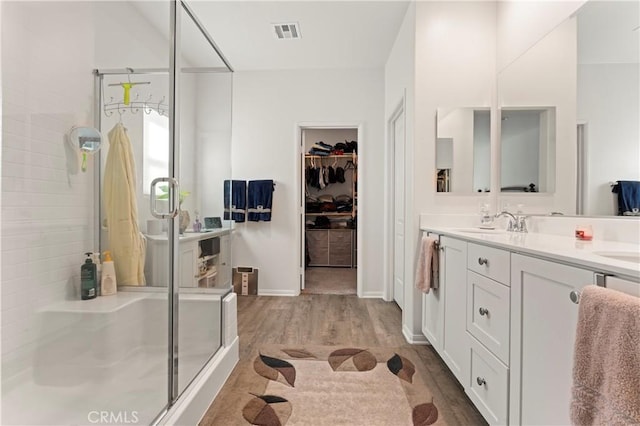 bathroom featuring vanity, a shower with shower door, and wood-type flooring