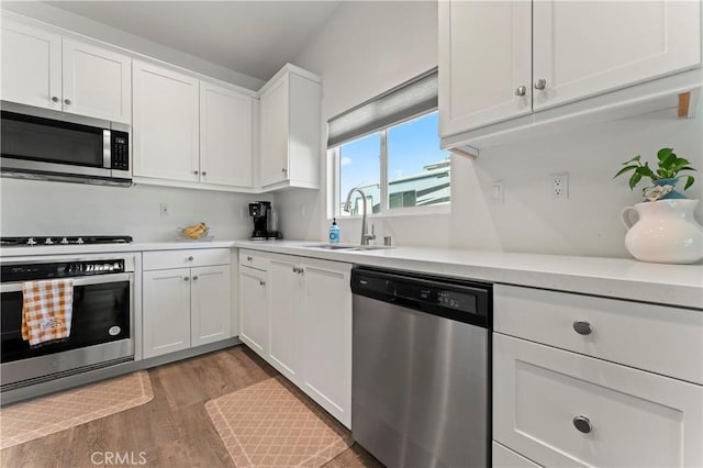 kitchen featuring stainless steel appliances, sink, hardwood / wood-style floors, and white cabinets