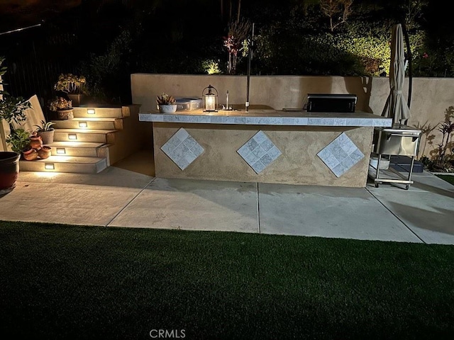 patio at night featuring an outdoor kitchen