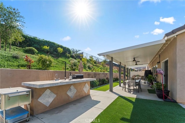 view of patio / terrace featuring an outdoor kitchen, ceiling fan, and sink