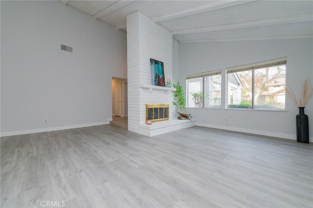 unfurnished living room featuring a brick fireplace, high vaulted ceiling, beam ceiling, and light hardwood / wood-style flooring