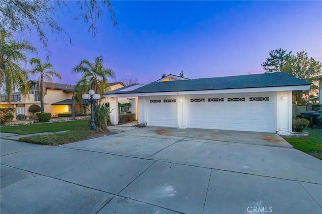 ranch-style house featuring a garage and a lawn