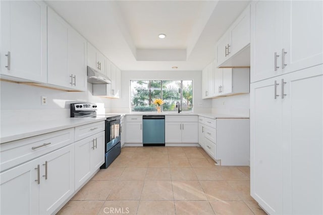 kitchen featuring stainless steel appliances, white cabinetry, light tile patterned floors, and a tray ceiling