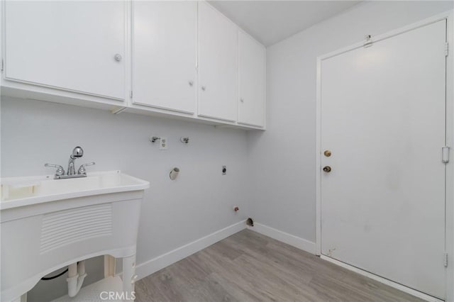 clothes washing area featuring gas dryer hookup, cabinets, light wood-type flooring, electric dryer hookup, and washer hookup