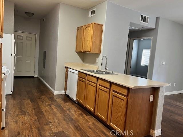 kitchen featuring dark hardwood / wood-style floors, sink, white appliances, and kitchen peninsula