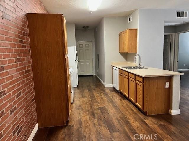 kitchen with sink, dishwasher, dark hardwood / wood-style floors, brick wall, and kitchen peninsula