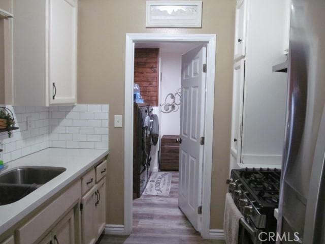 kitchen featuring sink, light hardwood / wood-style flooring, white cabinetry, stainless steel appliances, and tasteful backsplash