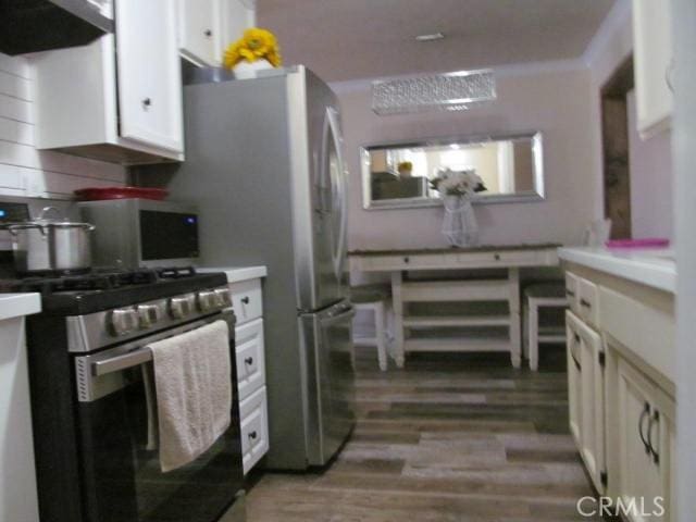 kitchen featuring stainless steel gas stove, extractor fan, white cabinetry, and light wood-type flooring