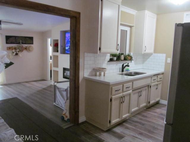 kitchen with white cabinetry, sink, stainless steel refrigerator, and light wood-type flooring