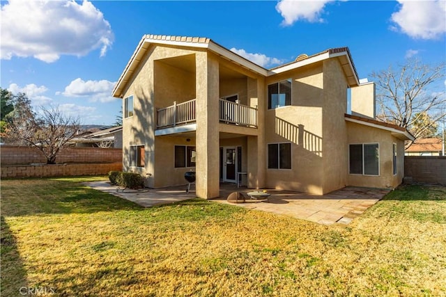 rear view of house with a balcony, a yard, and a patio area