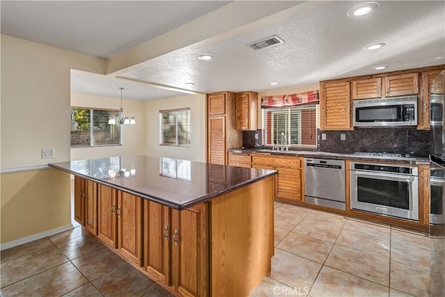 kitchen with sink, stainless steel appliances, tasteful backsplash, light tile patterned flooring, and dark stone counters