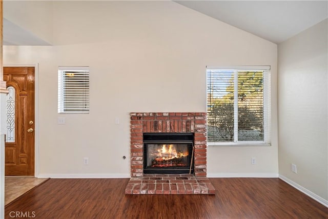 unfurnished living room with lofted ceiling, wood-type flooring, a brick fireplace, and plenty of natural light