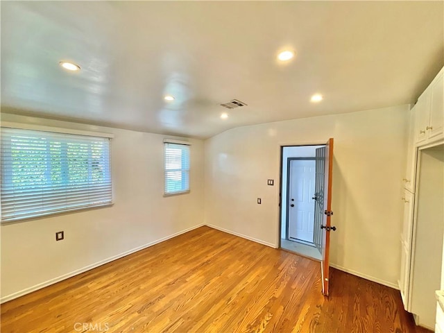 unfurnished room with lofted ceiling and light wood-type flooring