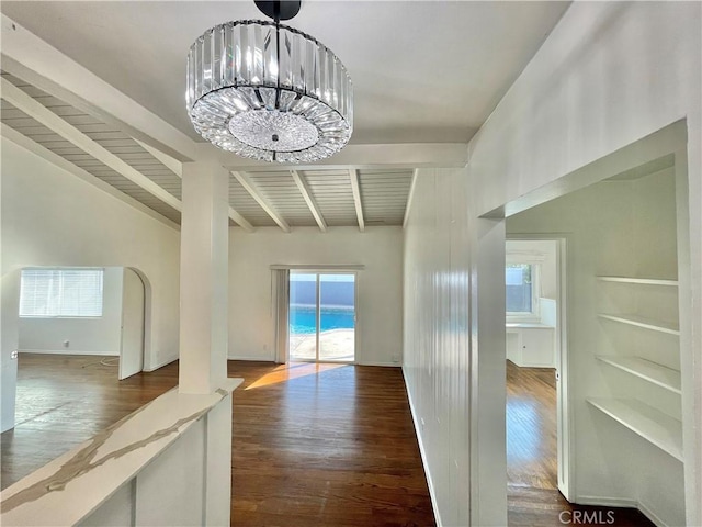 interior space featuring an inviting chandelier, vaulted ceiling with beams, and dark hardwood / wood-style flooring