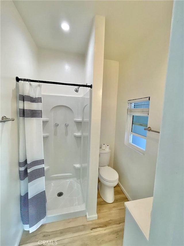 bathroom featuring walk in shower, wood-type flooring, and toilet