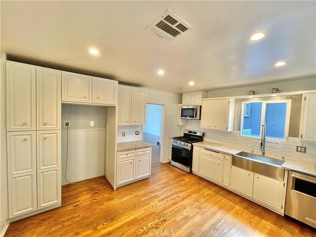 kitchen with light wood-type flooring, white cabinets, and appliances with stainless steel finishes