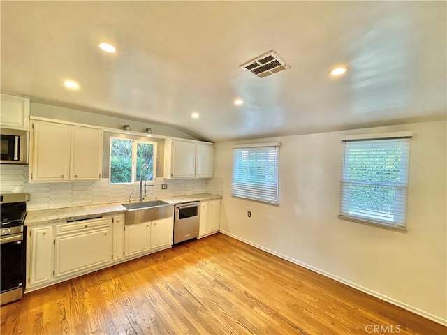 kitchen with stainless steel appliances, white cabinetry, and decorative backsplash