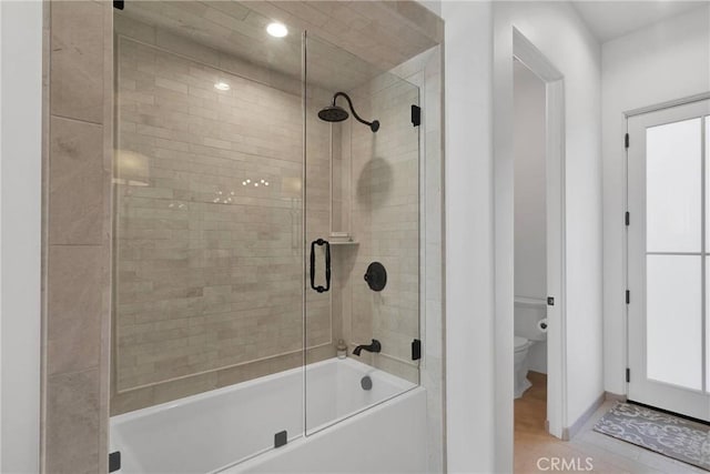 bathroom featuring hardwood / wood-style floors, bath / shower combo with glass door, and toilet