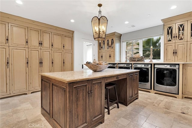 kitchen featuring an inviting chandelier, decorative light fixtures, a kitchen island, independent washer and dryer, and cream cabinetry