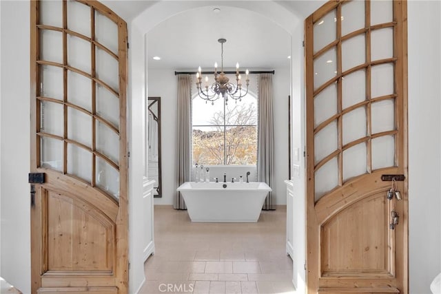 bathroom featuring a bath and an inviting chandelier