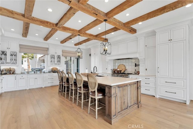 kitchen with a spacious island, a breakfast bar area, white cabinetry, light hardwood / wood-style flooring, and pendant lighting