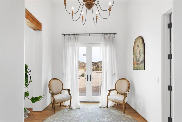 living area featuring hardwood / wood-style flooring, an inviting chandelier, and french doors