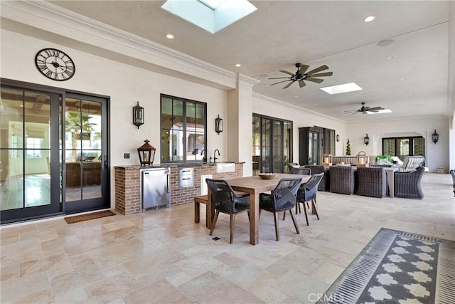 dining area with sink, a skylight, ornamental molding, and ceiling fan