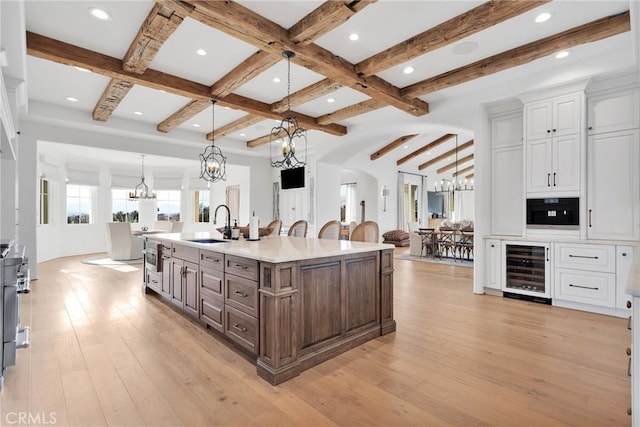 kitchen featuring beverage cooler, pendant lighting, white cabinets, and a chandelier